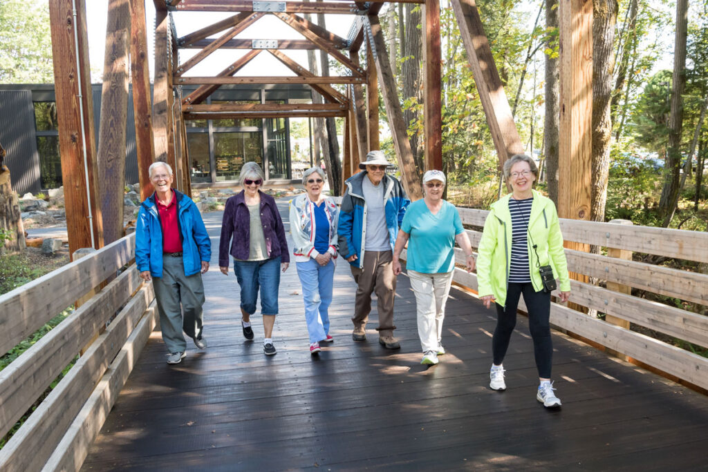 Men and women on a walk crossing a bridge